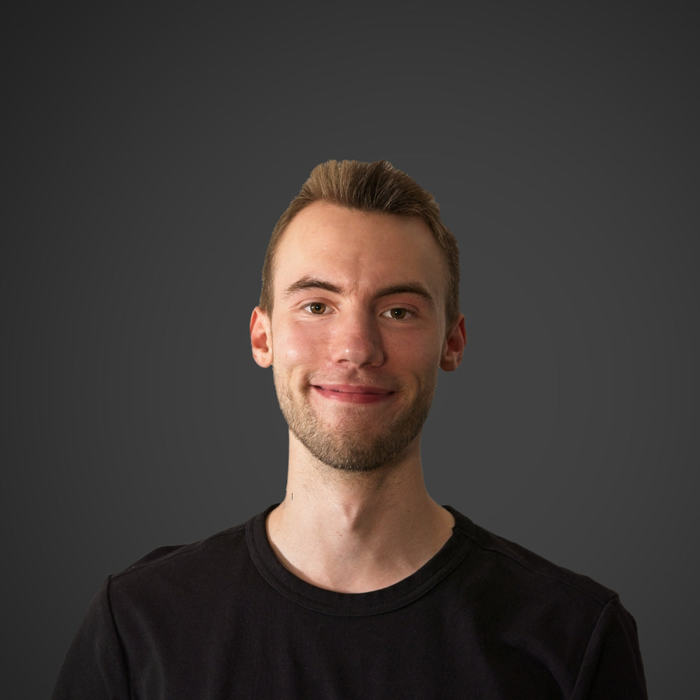 Junger Mann mit einem freundlichen Lächeln, kurzen blonden Haaren und schwarzem T-Shirt mit der Aufschrift "shopnative".