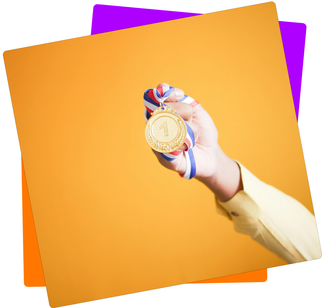 Ein nach oben ausgestreckter Arm hält vor orangenem Hintergrund eine goldene Medaille in die Luft. Das blau-weiß-rot-gestreifte Band der Medaille liegt fest in der Hand. Auf der Medaille ist die Zahl 1 zu sehen. 